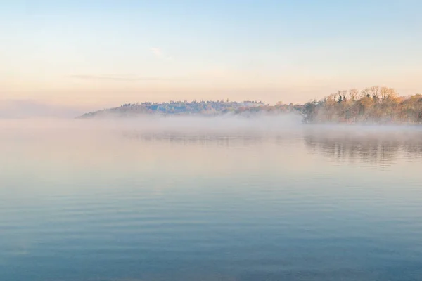 Zimny mglisty poranek nad jeziorem z odbiciami drzew . — Zdjęcie stockowe