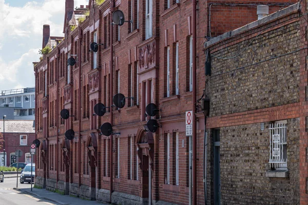 낡은 붉은 벽돌 건물 이 있고, 지팡이위에 많은 사탄 요리가 있다. — 스톡 사진