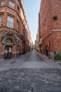 İki kırmızı tuğla bina arasında dar bir sokak. .