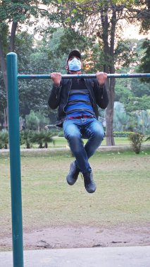 2021 yılında parkta maskeyle egzersiz yapan genç bir adam.