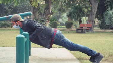 2021 yılında parkta maskeyle egzersiz yapan genç bir adam.