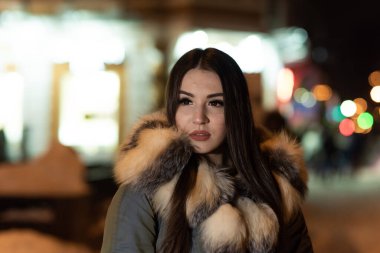 Yakın çekim kış portresi. Güzel genç bir kadın akşam caddesinde yürüyor. Şehir yaşam tarzı. Gece