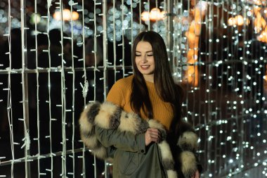 Güzel bir kızın portresi. Güzel esmer kadın, gece şehir ışıklarında portresi. Uzun siyah saçlı güzel bir kadının moda tarzı portresi. Şehir ışıkları