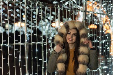 Güzel bir kızın portresi. Güzel esmer kadın, gece şehir ışıklarında portresi. Uzun siyah saçlı güzel bir kadının moda tarzı portresi. Şehir ışıkları