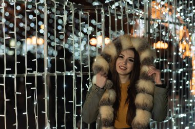 Güzel bir kızın portresi. Güzel esmer kadın, gece şehir ışıklarında portresi. Uzun siyah saçlı güzel bir kadının moda tarzı portresi. Şehir ışıkları