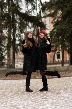 İki genç kız birlikte poz veriyor. İki kız kardeşin moda portresi sarılıyor ve kış zamanı eğleniyorlar, kürk manto giyiyorlar. En iyi arkadaşlar, dışarıda çiftler, karlı hava.