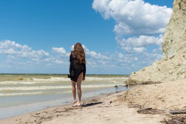 Siyah mayo giymiş ve deniz kenarında poz veren güzel bir kız. Seksi vücutlu genç bir kadın yaz tatilinde dinleniyor. Mayo konsepti. Yaz yaşam tarzı