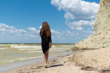 Siyah mayo giymiş ve deniz kenarında poz veren güzel bir kız. Seksi vücutlu genç bir kadın yaz tatilinde dinleniyor. Mayo konsepti. Yaz yaşam tarzı