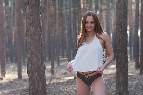 夏の森の中を歩くブラジャーと黒のパンティーのない白いシャツの誘惑的な女性 — ストック写真