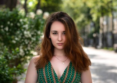 Genç kızıl saçlı bayan şehir caddesinde yürüyor.