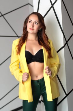 Siyah sutyenli, sarı ceketli, baştan çıkarıcı genç bir kadın. Stüdyoda seksi bir kadın.