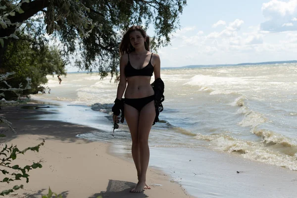 穿着黑色泳衣 穿着紧身衣 在海边摆姿势的性感美女 有性感身材的年轻女人在暑假休息 概念泳衣 夏季生活方式 — 图库照片