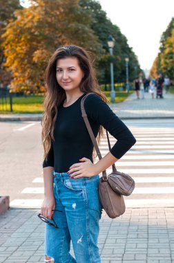 Uzun kıvırcık saçlı, sokakta yürüyen güzel bir genç kadın. 