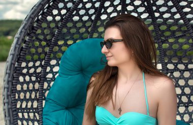 Havuz kenarında dinlenen şık bir mayo giymiş güzel bir bayan.