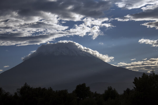 The majestic cone of El Misti Volcano in Arequipa, famous travel destination and landmark in Peru. Dramatic cloudy sky and fog on the bottom.