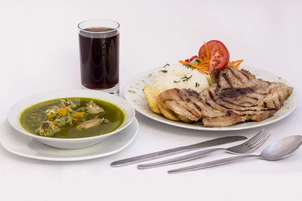 Plato peruano: Sopa de pollo de cilantro (aguadito de pollo) + chicha morada (jugo de maíz morado) y barbacoa a la parrilla con arroz, papas y ensalada . — Foto de Stock