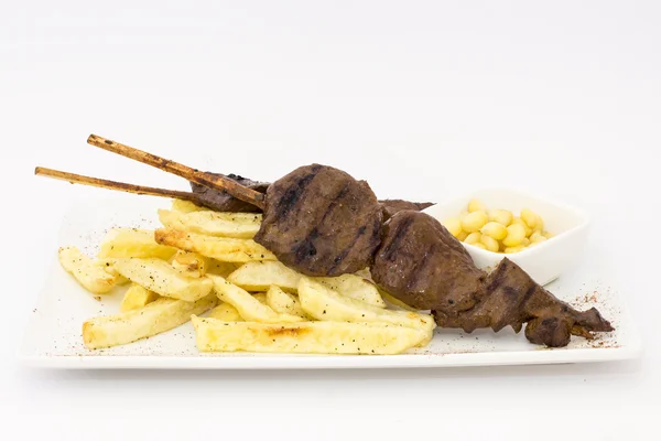 Anticuchos, cozinha peruana, carne grelhada de carne de vaca com batatas fritas (batatas fritas), milho branco e molho rocoto (pimenta) — Fotografia de Stock