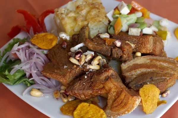 Peruvian food, fried pork (Chicharron) with potatoes, onion garnish, fried corn (canchita). — Stock Image Peruvian food, fried pork (Chicharron) with potatoes, onion garnish, fried corn (canchita). Stock Image