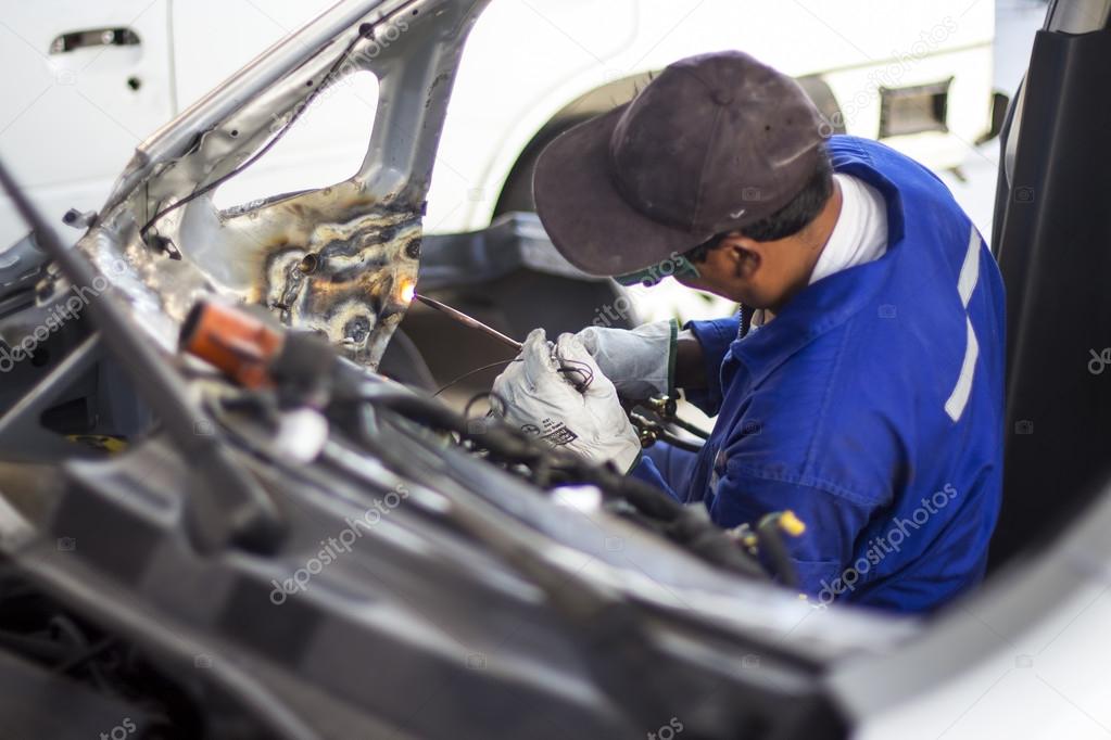 Man mechanical worker repairing a car body in a garage - Safety at work with protection wear. Welding work