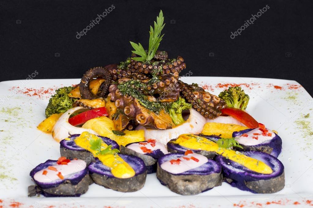 Grilled Octopus, gourmet dish from Peru. Served with purple potatoes (nativa), huancaina sauce, rice, onion,  vegetables