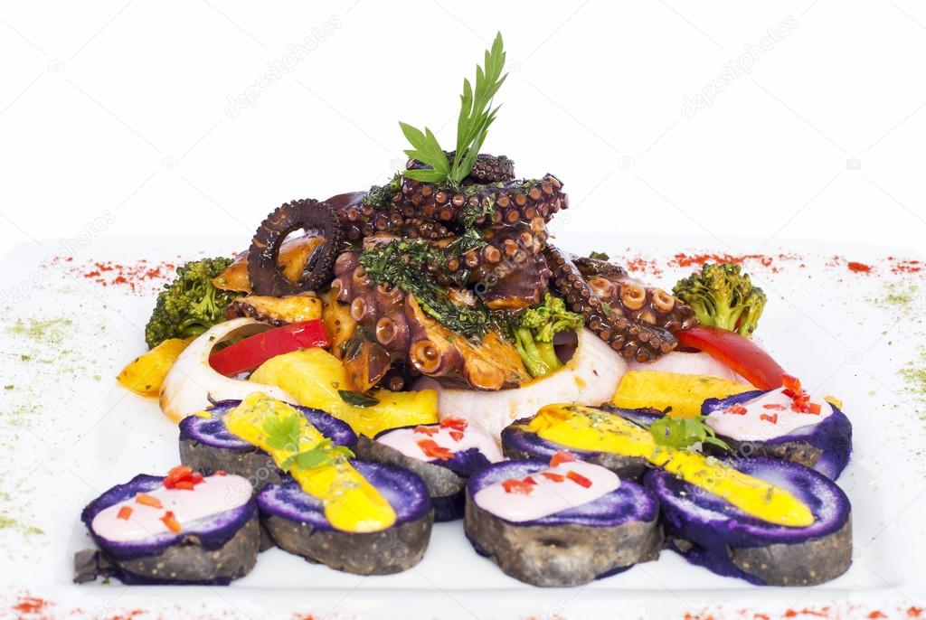 Grilled Octopus, gourmet dish from Peru. Served with purple potatoes (nativa), huancaina sauce, rice, onion,  vegetables