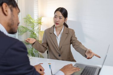 İki iş adamı modern bir ofiste finansal çizelge ve stratejileri tartışıyor. Resmi bir toplantıda fikir alışverişinde bulunur, raporları analiz eder ve çözümleri müzakere ederler..