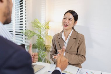 İki meslektaş başarılı tartışmayı neşeli ifadeler ve alkışlarla kutluyor. Olumlu etkileşimleri raporları inceledikten sonra takım çalışması, motivasyon ve memnuniyeti yansıtır..