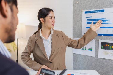 İş arkadaşları aktif olarak ortak bir toplantıda, çizelgeleri gözden geçiriyorlar, verilere işaret ediyorlar ve fikir alışverişinde bulunuyorlar. Takım çalışmaları strateji planlaması, analiz ve işbirliğini yansıtır..