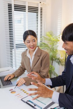 İş arkadaşları aktif olarak ortak bir toplantıda, çizelgeleri gözden geçiriyorlar, verilere işaret ediyorlar ve fikir alışverişinde bulunuyorlar. Takım çalışmaları strateji planlaması, analiz ve işbirliğini yansıtır..