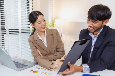 İki iş adamı, modern bir ofiste mali tablolar ve raporları tartışıyor. Birlikte çalışırlar, fikirleri paylaşırlar ve birlikte verileri analiz ederler, takım çalışmasını ve stratejisini vurgularlar..