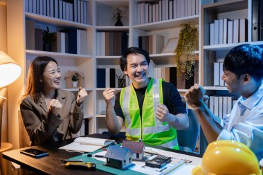 Mimarlar ve mühendisler planlarını gözden geçirmek, fikir alışverişinde bulunmak ve şehir ortamında çağdaş bir inşaat projesi için planlarını geliştirmek için bir ofiste birlikte çalışırlar..