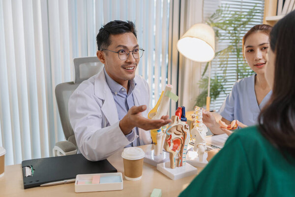 Врач преподает медицинскую команду во время клинического сеанса. Специалисты здравоохранения учатся вместе, обсуждая анатомические модели и случаи пациентов для повышения медицинских знаний и навыков лечения.