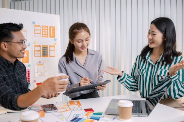 UX / UI tasarımcıları bir yaratıcı atölye sırasında uygulama geliştirme için arayüz fikirlerini test etmek ve geri bildirim alışverişinde bulunmak, takım çalışmasını ve yenilikçi tasarım düşüncesini vurgulamak için işbirliği yaparlar.