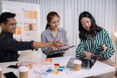 UX / UI tasarımcıları son tasarım projelerini takıma sunar, uygulama arayüzü ekranlarını gösterir ve profesyonel yaratıcı ofis ortamında kullanıcı deneyimi stratejilerini açıklar.