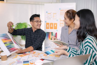 UX / UI tasarımcıları son tasarım projelerini takıma sunar, uygulama arayüzü ekranlarını gösterir ve profesyonel yaratıcı ofis ortamında kullanıcı deneyimi stratejilerini açıklar.