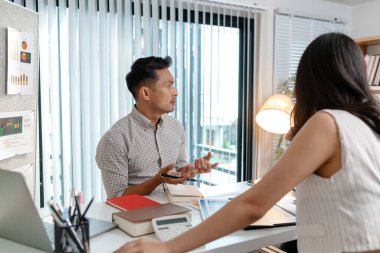 Modern bir ofiste veri ve pazarlama raporlarını tartışan bir grup çok kültürlü meslektaşım. Ekip performans çizelgelerini analiz etmeye ve iş büyümesi için planlama stratejilerine odaklanıyor.