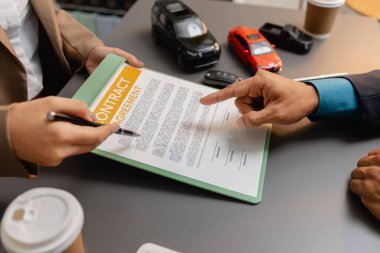 Bir araba satıcısı ve bir müşteri arasında bir iş görüşmesi. Araç satın alma anlaşmasını tartışıyorlar. Sözleşme imzalanmadan önce gözden geçiriliyor ve açıklanıyor, güven ve işbirliğini temsil ediyor.