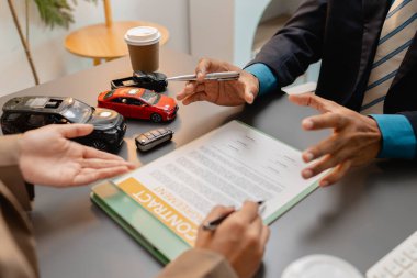 Bir araba satıcısı ve bir müşteri arasında bir iş görüşmesi. Araç satın alma anlaşmasını tartışıyorlar. Sözleşme imzalanmadan önce gözden geçiriliyor ve açıklanıyor, güven ve işbirliğini temsil ediyor.