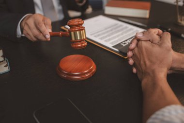 Profesyonel bir avukat bir ofiste müvekkil ile hukuki konuları tartışıyor, yasal danışmanlık ve belge inceleme hizmetleri sunuyor, adaleti, güveni ve profesyonel danışmayı sembolize ediyor.