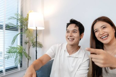 Genç bir çift kanepede birlikte oturur, rahat bir oturma odasında mutlu bir şekilde televizyon izlerler. Adam uzaktan kumandayı tutarken hem gülümseyip hem de rahat ve dost canlısı bir atmosferde gösterinin tadını çıkarıyor..