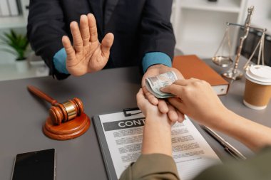 Bir avukat, müvekkilinden rüşvet teklif eden bir bürodan para almayı reddediyor. Görüntü, hukuk ve iş sektörlerinde etik, dürüstlük ve yolsuzlukla mücadeleyi simgeliyor..