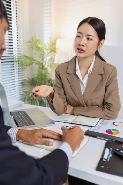 İş arkadaşları renkli çizelge ve raporları gözden geçirmek için finansal bir toplantıdalar. Etkili sonuçlar elde etmek için fikir alışverişinde bulunur, notlar alır ve stratejileri analiz ederler..