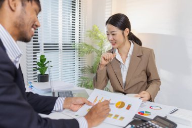 İş arkadaşları renkli çizelge ve raporları gözden geçirmek için finansal bir toplantıdalar. Etkili sonuçlar elde etmek için fikir alışverişinde bulunur, notlar alır ve stratejileri analiz ederler..