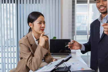 İş arkadaşları ortak bir tartışma içindeler, finansal tabloları ve raporları analiz ediyorlar. Fikir alışverişinde bulunurlar, stratejileri gözden geçirirler ve gelecekteki hedefleri planlarlar..