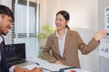 İş arkadaşları aktif olarak ortak bir toplantıda, çizelgeleri gözden geçiriyorlar, verilere işaret ediyorlar ve fikir alışverişinde bulunuyorlar. Takım çalışmaları strateji planlaması, analiz ve işbirliğini yansıtır..