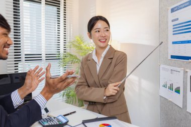 İş arkadaşları aktif olarak ortak bir toplantıda, çizelgeleri gözden geçiriyorlar, verilere işaret ediyorlar ve fikir alışverişinde bulunuyorlar. Takım çalışmaları strateji planlaması, analiz ve işbirliğini yansıtır..