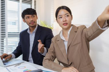 Ciddi bir ofis tartışmasına katılan bir grup profesyonel, mali raporları analiz ediyor ve sorunları çözmek ve etkili kurumsal kararlar almak için fikir alışverişinde bulunuyor..