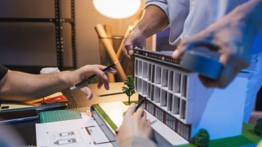 Bir grup mühendis ve mimar, yaratıcı bir takım çalışması ortamında yenilikçi modern binalar tasarlamak için fikirleri tartışıyor ve teknik planlar paylaşıyor..