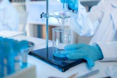 Bilimsel ekipman ve test tüpleriyle çevrili bir laboratuvarda kimya araştırmacısı, yenilikleri, bilimsel gelişimi ve modern tıbbi araştırma ortamını temsil ediyor..