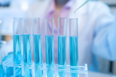 Bilimsel ekipman ve test tüpleriyle çevrili bir laboratuvarda kimya araştırmacısı, yenilikleri, bilimsel gelişimi ve modern tıbbi araştırma ortamını temsil ediyor..